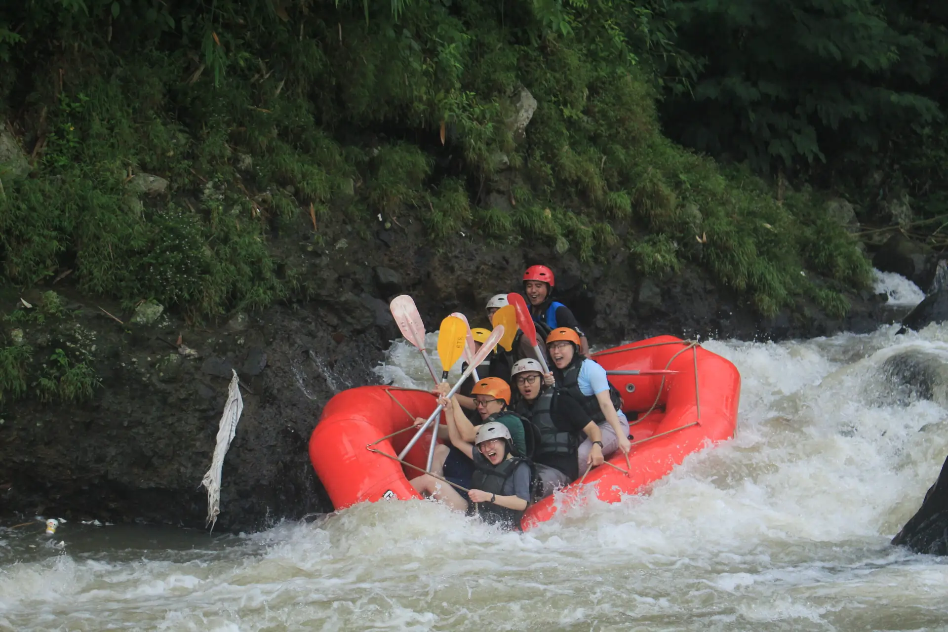 Perahu merah melewati batu besar di tengah arus