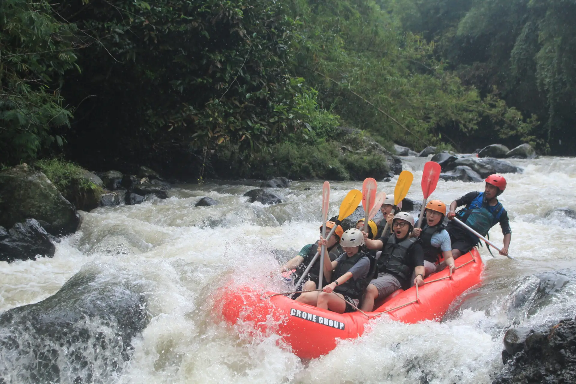 Empat peserta mendayung perahu merah di sungai berbatu